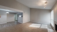 Located at 2720 S Broadway Ave in Tyler, TX, this two-story home offers four bedrooms and two full bathrooms across a well-distributed layout. The main floor, which comprises the majority of the living space, features a combined kitchen and living room area anchored by a tile-surround fireplace with large windows that invite abundant natural light. Vaulted ceilings in the living area add a sense of openness and volume, complemented by plush carpet flooring and neutral-toned walls throughout.

The kitchen is equipped with gray shaker-style cabinetry, stone-look countertops, a stainless sink, and black appliances including an electric range. A peninsula counter connects the kitchen to the adjacent living area, creating a practical open-concept flow. Wood-look flooring runs through the kitchen and dining space.

Both bathrooms are clean and functional, featuring white shaker vanities with marble-look countertops, framed mirrors, and tub-shower combinations set on wood-look tile flooring. The bedrooms are carpeted and well-sized, with the generously proportioned primary bedroom offering a closet and windows with outdoor views. Secondary bedrooms include ceiling fans and good natural light. A staircase connects the main floor to the upper level, where additional bedrooms are located.