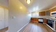 This single-floor residence offers three bedrooms, one bathroom, and a practical layout designed for comfortable everyday living. The kitchen is a standout feature, equipped with warm honey-toned wood cabinetry — including glass-front upper cabinets — light countertops, and a full suite of appliances including a gas range, dishwasher, refrigerator, and microwave. A window above the sink fills the kitchen with natural light, while durable wood-look flooring ties the space together with a clean, modern aesthetic. Hallways connect the main living areas, providing an efficient flow throughout the unit. The bedrooms are carpeted and feature neutral walls with sliding glass-door closets and windows that frame outdoor greenery, creating a calm, airy atmosphere. The spacious primary bedroom offers generous room for furnishings. The bathroom is finished with a sliding glass shower-tub enclosure, white fixtures, a vanity, and wood-look flooring for a crisp, clean look. Throughout the residence, textured ceilings, flush-mount lighting, and consistent warm-toned walls contribute to a cohesive and inviting interior. The layout is efficient and well-organized, making the most of the available space across all rooms.