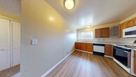 This single-floor residence offers three bedrooms, one bathroom, and a practical layout designed for comfortable everyday living. The kitchen is a standout feature, equipped with warm honey-toned wood cabinetry — including glass-front upper cabinets — light countertops, and a full suite of appliances including a gas range, dishwasher, refrigerator, and microwave. A window above the sink fills the kitchen with natural light, while durable wood-look flooring ties the space together with a clean, modern aesthetic. Hallways connect the main living areas, providing an efficient flow throughout the unit. The bedrooms are carpeted and feature neutral walls with sliding glass-door closets and windows that frame outdoor greenery, creating a calm, airy atmosphere. The spacious primary bedroom offers generous room for furnishings. The bathroom is finished with a sliding glass shower-tub enclosure, white fixtures, a vanity, and wood-look flooring for a crisp, clean look. Throughout the residence, textured ceilings, flush-mount lighting, and consistent warm-toned walls contribute to a cohesive and inviting interior. The layout is efficient and well-organized, making the most of the available space across all rooms.