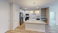 Located in Fort Mill, SC, this single-floor residence offers a well-designed, open-concept layout with a clean, neutral color palette throughout. The kitchen serves as a central highlight, equipped with stainless steel appliances including a side-by-side refrigerator with ice dispenser, an electric range, and a built-in microwave. White cabinetry, granite countertops, a subway tile backsplash, and a large kitchen island with pendant lighting make this space both functional and visually appealing. Open shelving adds additional storage and display options. Hardwood-style flooring flows through the living and kitchen areas, while plush carpeting provides comfort in the bedrooms. The bedrooms are generously sized, with multiple windows fitted with white blinds that allow for an abundance of natural light. Closet space is well-provided, including a walk-in closet accessible from one of the bedrooms. The bathrooms feature granite-topped vanities with white cabinetry, hardwood-style flooring, and one includes a soaking tub and shower combination. A walk-in closet with built-in shelving connects to the primary bath. In-wall speakers in the living area add a modern touch. The overall ambiance is bright, clean, and move-in ready.