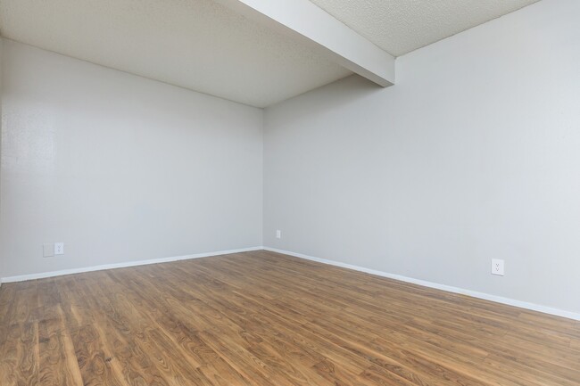 This expansive living room offers a modern, minimalist design with beautiful hardwood floors and ample natural light. Whether you’re relaxing or entertaining, this open layout provides endless possibilities for comfort and style. - Casa Del Sol