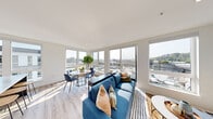 Located on an upper floor in Seattle's vibrant University District, this contemporary residence at 4906 25th Ave NE offers a thoughtfully designed layout bathed in natural light. The open-concept living and dining area is anchored by expansive floor-to-ceiling windows on multiple walls, framing sweeping views of the surrounding Seattle cityscape and letting sunlight pour across the light hardwood flooring throughout.

The gourmet kitchen is a standout feature, appointed with dark, flat-front cabinetry, a full suite of stainless steel appliances, a white subway tile backsplash, and a generously sized island topped with striking white marble-veined countertops — ideal for both cooking and casual dining with its built-in bar seating.

The unit includes two well-proportioned bedrooms, each with large windows that bring in abundant natural light and views of the neighborhood. The primary bathroom is finished with wood-look flooring, a sleek dark vanity with light countertops, and a glass-enclosed walk-in shower with tiled surround. An in-unit laundry area with a stacked washer and dryer adds everyday convenience. The clean, neutral palette and modern finishes throughout create a cohesive, contemporary ambiance well-suited to urban living in Seattle.