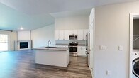 Located in Suamico, WI, this 1-bedroom, 1-bathroom residence offers a thoughtfully designed open-concept layout across a single floor. The combined kitchen and living area serves as the heart of the home, anchored by a sleek fireplace and expansive sliding glass doors that flood the space with natural light and offer views of the surrounding greenery. The kitchen is well-appointed with white shaker cabinetry reaching toward the ceiling, granite countertops, stainless steel appliances including a range, built-in microwave, and refrigerator, and a center island with an undermount sink — ideal for both cooking and casual dining. Durable wood-look flooring runs throughout the entire residence, lending a cohesive and modern aesthetic. The living room features baseboard heating and a wall-mounted mini-split unit for year-round climate comfort. The generously sized bedroom receives abundant natural light through a large window, is served by a ceiling fan, and connects to a dedicated closet. The bathroom mirrors the kitchen's design sensibility with granite countertops, white cabinetry, and consistent wood-look flooring. Clean neutral walls and bright finishes throughout create a fresh, move-in-ready atmosphere.