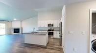 Located in Suamico, WI, this 1-bedroom, 1-bathroom residence offers a thoughtfully designed open-concept layout across a single floor. The combined kitchen and living area serves as the heart of the home, anchored by a sleek fireplace and expansive sliding glass doors that flood the space with natural light and offer views of the surrounding greenery. The kitchen is well-appointed with white shaker cabinetry reaching toward the ceiling, granite countertops, stainless steel appliances including a range, built-in microwave, and refrigerator, and a center island with an undermount sink — ideal for both cooking and casual dining. Durable wood-look flooring runs throughout the entire residence, lending a cohesive and modern aesthetic. The living room features baseboard heating and a wall-mounted mini-split unit for year-round climate comfort. The generously sized bedroom receives abundant natural light through a large window, is served by a ceiling fan, and connects to a dedicated closet. The bathroom mirrors the kitchen's design sensibility with granite countertops, white cabinetry, and consistent wood-look flooring. Clean neutral walls and bright finishes throughout create a fresh, move-in-ready atmosphere.
