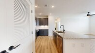 This well-appointed 1-bedroom, 1-bathroom unit offers a thoughtfully designed single-floor layout that maximizes every square foot. The open-concept kitchen and living area serves as the heart of the home, featuring warm, light hardwood-style flooring that extends throughout the main living spaces. The kitchen is a standout, showcasing dark gray shaker-style cabinetry reaching toward the ceiling, a classic white subway tile backsplash, and a large granite-topped island with an undermount sink and matte black faucet. A full suite of stainless steel appliances — including a side-by-side refrigerator, range, microwave, and dishwasher — completes this highly functional cooking space. The adjoining living area is bright and open, with recessed lighting and a clean white palette that enhances the sense of space. The bedroom offers plush carpeting, natural light from dual windows with blinds, a ceiling fan, and direct access to both a closet and the bathroom. The bathroom is finished with matching gray cabinetry, granite countertops, large-format tile surrounding the soaking tub and shower, and coordinating matte black fixtures. A dedicated closet adds practical storage to round out this move-in-ready residence.