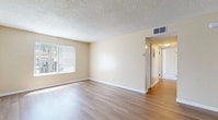 This single-floor, 3-bedroom, 2-bathroom home offers a practical and comfortable layout across a well-utilized footprint. The living room features light wood-style flooring, neutral warm-toned walls, a textured ceiling, and a large window with vertical blinds that allows ample natural light to filter in. A hallway connects the main living areas to the private quarters, providing a clear and functional flow throughout the home.

The kitchen is configured in a galley style, featuring warm wood cabinetry on both sides, light countertops, a built-in dishwasher, a refrigerator, and a sink with overhead fluorescent lighting — offering efficient use of space for meal preparation.

The three bedrooms are finished with plush carpeting and include windows with vertical blinds for natural light and privacy. The generously sized primary bedroom features a mirrored sliding closet and a ceiling fan, while the additional bedrooms also include closet storage and ceiling fans in select rooms.

The two bathrooms are clean and functional. One includes a walk-in glass-panel shower stall with wood-style flooring, while the other features a white vanity with a mirrored medicine cabinet, a toilet, and matching flooring. Neutral beige tones carry throughout the home, creating a cohesive and inviting atmosphere.