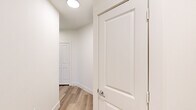 This thoughtfully designed single-story home offers two bedrooms, two bathrooms, and a functional layout across a comfortable footprint. The interior is defined by a cohesive, modern aesthetic with neutral tones, light hardwood-style flooring, and crisp white trim throughout.

The kitchen is a standout space, featuring grey shaker-style cabinetry with matte black hardware, light granite countertops, a decorative tile backsplash, and stainless steel appliances including a refrigerator and dishwasher. A central island with a built-in cooktop and pendant lighting above adds both style and practicality, while a window above the sink brings in natural light.

The living area benefits from large windows fitted with horizontal blinds, allowing for ample natural light and a bright, airy feel. The bedrooms are carpeted for comfort, with the primary bedroom offering a ceiling fan and a dedicated bathroom featuring white shaker vanity cabinetry, granite countertops, a framed mirror, and wood-look flooring. Two closets provide generous storage throughout the home.

Connecting the spaces are clean, well-lit hallways with light-toned flooring and panel doors, reinforcing the home's modern and move-in-ready character.