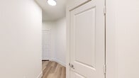 This thoughtfully designed single-story home offers two bedrooms, two bathrooms, and a functional layout across a comfortable footprint. The interior is defined by a cohesive, modern aesthetic with neutral tones, light hardwood-style flooring, and crisp white trim throughout.

The kitchen is a standout space, featuring grey shaker-style cabinetry with matte black hardware, light granite countertops, a decorative tile backsplash, and stainless steel appliances including a refrigerator and dishwasher. A central island with a built-in cooktop and pendant lighting above adds both style and practicality, while a window above the sink brings in natural light.

The living area benefits from large windows fitted with horizontal blinds, allowing for ample natural light and a bright, airy feel. The bedrooms are carpeted for comfort, with the primary bedroom offering a ceiling fan and a dedicated bathroom featuring white shaker vanity cabinetry, granite countertops, a framed mirror, and wood-look flooring. Two closets provide generous storage throughout the home.

Connecting the spaces are clean, well-lit hallways with light-toned flooring and panel doors, reinforcing the home's modern and move-in-ready character.