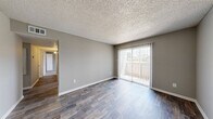 This 2-bedroom, 2-bathroom carriage-style unit in Nederland, TX offers a well-designed, single-floor layout that maximizes every inch of its comfortable footprint. The living area features rich hardwood-style flooring, neutral gray walls, and a textured ceiling, creating a clean and inviting atmosphere. A sliding glass door opens to a private balcony, allowing natural light to fill the space and providing a pleasant outdoor view.

The kitchen is efficiently laid out with dark espresso-toned cabinetry, light speckled countertops, a double-basin sink, and a breakfast bar that connects the kitchen to the dining area. A ceiling fan adds to the functionality of this space. Both bedrooms are carpeted for comfort and include ceiling fans with light fixtures. Each bedroom benefits from natural light through window blinds, and the primary bedroom features a walk-in closet with dual hanging rods and built-in shelving for ample storage.

The bathrooms are clean and practical, featuring white tiled tub-shower combinations, dark cabinetry for storage, and wood-style flooring. A hallway connects the main living areas to the bedrooms and bathrooms, contributing to an efficient flow throughout the unit. The overall aesthetic is neutral and move-in ready, offering a functional and comfortable living environment.