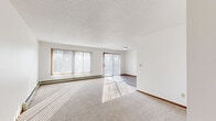 This 2-bedroom, 1-bathroom unit at 4901 S Marion Rd in Sioux Falls, SD offers a practical and comfortable single-floor layout. The spacious living room is a standout feature, bathed in natural light streaming through large windows and a sliding glass door fitted with vertical blinds, which also provides outdoor access. A baseboard heating system runs along the perimeter, and neutral carpet flooring adds warmth to the space.

The kitchen is efficiently designed with rich dark-wood cabinetry, light granite-style countertops, wood-look tile flooring, and a full suite of white appliances including a range, over-the-range microwave, dishwasher, and refrigerator. It opens toward the rest of the living area, creating a connected flow throughout the unit.

Both bedrooms feature plush carpeting, closets, and baseboard heating. The primary bedroom is generously sized and well-lit, while the second bedroom includes a window with natural light. Two closets provide ample storage throughout the unit.

The bathroom is clean and functional, featuring a tub/shower combo, a dark-wood vanity with a granite-style countertop, a large mirror, wood-look flooring, and baseboard heating. The entryway transitions seamlessly between the carpeted living space and hard-surface flooring, completing this well-appointed unit.