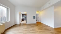 Located at 7 DeKalb Avenue in Brooklyn's vibrant downtown neighborhood, this studio offers a well-designed, single-floor layout that maximizes both function and comfort. Throughout the space, light-toned hardwood flooring creates a warm, cohesive foundation that ties each area together seamlessly.

The open living area is bright and airy, benefiting from large windows that frame impressive views of the New York City skyline, flooding the room with natural light. Clean white walls and a neutral palette enhance the sense of openness throughout. An electrical panel is conveniently recessed into the wall.

The separate kitchen is thoughtfully appointed with dark espresso-toned cabinetry, light gray countertops, and a subtle teal subway tile backsplash. Stainless steel appliances — including a gas range, built-in microwave, dishwasher, and full-size refrigerator — deliver a modern, fully equipped cooking environment. A window in the kitchen provides additional natural light.

A welcoming entryway leads into the main living space, offering a clear sense of arrival. The overall layout is efficiently organized, with a dedicated corridor connecting the living area, kitchen, and additional spaces, making this studio a practical and stylish option in one of Brooklyn's most dynamic and well-connected neighborhoods.