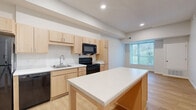 This 1-bedroom, 1-bathroom unit at 2840 N Wayzata Blvd in Minneapolis, MN offers a clean, modern aesthetic throughout its efficiently designed single-floor layout. Light hardwood flooring flows seamlessly through each room, creating a warm and cohesive feel.

The kitchen serves as a central highlight, featuring light maple cabinetry, white countertops, a full suite of black appliances including a range, microwave, dishwasher, and refrigerator, as well as a deep undermount sink. A freestanding kitchen island with a white surface provides additional prep space and a casual dining option, while a large window fills the area with natural light and outdoor views.

The entry area transitions smoothly into the main living space, which is open and airy with clean white walls and recessed lighting. The bedroom is a comfortable, well-proportioned room with a window overlooking greenery, offering a peaceful retreat with access to a dedicated walk-in closet. Notably, the unit includes three closets in total, providing exceptional storage throughout.

The bathroom is finished with a light wood vanity, a walk-in shower with a clean white surround, and accessible grab bars, reflecting a thoughtful, functional design. A hallway connects the living areas efficiently, completing this well-organized and move-in-ready home.