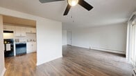 Located at 1874 Sunset Ave in Cincinnati, Ohio, this single-floor, two-bedroom, one-bathroom residence offers a practical and well-organized layout. Throughout the home, wood-look plank flooring provides a clean, consistent aesthetic, complemented by neutral white walls and textured ceilings.

The living room is a comfortable, open space featuring a ceiling fan with light fixture, a wall-mounted AC unit, and a baseboard heating system. Natural light enters through windows with views of surrounding greenery, creating a bright and welcoming atmosphere.

The kitchen is well-appointed with crisp white shaker-style cabinetry, light countertops, and a full suite of black appliances including a refrigerator, electric range with overhead ventilation, and a dishwasher. A double-basin sink rounds out this functional cooking space.

The primary bedroom is a generously sized room with wood-look flooring and a large closet featuring dual hanging rods and built-in shelving, offering ample storage. The second bedroom also features the same durable flooring and benefits from natural light. The bathroom includes a full tub-shower combination with white tile surround, keeping with the home's clean, bright aesthetic throughout.