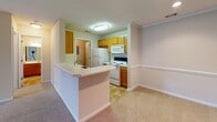 Located at 771 E Butler Rd in Mauldin, South Carolina, this single-floor residence offers a functional and comfortable layout throughout. The open-concept kitchen is equipped with warm honey-toned cabinetry, white appliances including a range, microwave, and refrigerator, and features tile flooring with a peninsula breakfast bar that connects seamlessly to the adjacent living area. The living space is finished with neutral carpet and recessed lighting, complemented by a chair-rail accent along the walls, creating a clean and classic aesthetic. A dedicated entry area with an electrical panel is conveniently accessible from the kitchen. The bedrooms are generously sized, each featuring plush carpeting, ceiling fans, and exterior-facing windows with blinds that allow for natural light. One bedroom provides direct outdoor access through a glass-paneled door. The bathroom is well-appointed with warm wood vanity cabinetry, a solid-surface countertop, a large vanity mirror with overhead lighting, and tile flooring. Throughout the space, neutral tones, textured ceilings, and consistent trim work contribute to a cohesive and move-in-ready environment suited for comfortable everyday living.