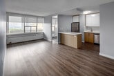 Located at 255 Main St in Toronto's East End, this thoughtfully updated 3-bedroom, 1-bathroom unit offers a functional and modern living experience across a single floor. The open-concept layout connects the living room and kitchen seamlessly, with light grey walls, a textured ceiling, and durable wood-look flooring running throughout. The kitchen is well-appointed with two-tone cabinetry — crisp white upper cabinets paired with warm wood-grain lower units — along with a clean white quartz countertop, stainless steel appliances including a refrigerator, dishwasher, and range, plus a peninsula that provides additional workspace and casual seating. Each of the three bedrooms features large windows fitted with roller blinds, baseboard heating, and mirrored sliding closet doors that enhance the sense of space. The primary bedroom offers elevated views of the Toronto skyline and surrounding greenery. The bathroom is finished in a clean, contemporary style with a wide-format vanity mirror, wood-grain cabinetry, quartz countertop, undermount sink, and tiled shower surround. A central hallway with mirrored closet doors connects the bedrooms efficiently. The unit's elevated position and window placement allow for natural light throughout the day.