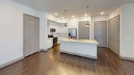 This single-floor residence offers a thoughtfully designed layout with modern finishes and a cohesive aesthetic throughout. The open-concept kitchen serves as a centerpiece, featuring crisp white shaker cabinetry, granite countertops, stainless steel appliances including a range, over-the-range microwave, and a French door refrigerator with an ice dispenser. A large center island with pendant lighting above and an integrated sink adds both functionality and style, while wood-look flooring ties the space together seamlessly.

The bedrooms are generously proportioned, with plush carpeting underfoot and ceiling fans overhead. Several rooms offer direct access to a private balcony through glass French doors, allowing natural light to fill the space. Walk-in closets with built-in shelving provide ample storage.

The bathrooms are finished with granite-topped white vanities, tile-surround soaking tubs, and wood-look flooring. Open shelving adds practical storage in a clean, modern presentation. One bathroom features an extended vanity with a framed mirror, while the other includes convenient over-toilet shelving.

Throughout the residence, neutral tones, recessed lighting, and consistent hardwood-style flooring create a bright, cohesive, and welcoming atmosphere suited for comfortable everyday living.