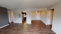This single-floor residence at 2026 W Algonquin Rd in Mount Prospect, IL offers a well-organized layout with a cohesive, modern aesthetic throughout. The open-concept living and dining area is expansive, finished with rich dark hardwood-style flooring that extends throughout the main living spaces, creating a warm and inviting atmosphere. A ceiling fan overhead adds both function and visual appeal, while ample wall space and multiple vents ensure year-round comfort. An electrical panel is conveniently accessible within the living area.

The kitchen is thoughtfully designed with dark espresso cabinetry, white countertops, and a neutral mosaic tile backsplash that adds texture and character. Stainless steel appliances—including a refrigerator, range, microwave, and dishwasher—lend a contemporary feel. A peninsula counter provides additional prep space and a natural transition between the kitchen and living area.

The bedroom is generously sized, finished with soft carpet and a window that allows natural light and outdoor views. Two bathrooms serve the unit: a half bath featuring a dark vanity, framed mirror, and tile flooring, and a full bath with a marble-look countertop, dark cabinetry, and slate-style tile flooring, offering a refined, functional finish throughout.