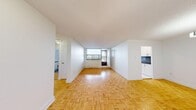 This single-floor, one-bedroom, one-bathroom unit offers a practical and well-organized layout across a comfortable footprint. The living room is the heart of the space, showcasing warm parquet flooring in a classic herringbone-style pattern that extends throughout the unit. Large windows flood the area with natural light and frame open outdoor views, while a pendant light fixture illuminates the entryway side of the room.

The galley-style kitchen has been thoughtfully renovated with white cabinetry extending to the ceiling, dark countertops, a mosaic tile backsplash, and marble-look porcelain tile flooring. Stainless steel appliances, including a range, over-the-range microwave, and a single-basin sink, complete the functional setup.

The bedroom is a well-proportioned, quiet retreat featuring the same parquet flooring, a large window with elevated outdoor views, and a baseboard heating unit. A dedicated closet provides convenient storage. The bathroom is clean and bright, featuring a full soaker tub with a shower, white subway-style wall tiles accented by a decorative mosaic border, and modern chrome fixtures. A hallway connects all rooms, contributing to the unit's efficient and logical flow.