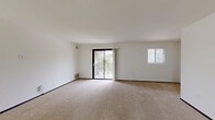 Located in Greenfield, Wisconsin, this 2-bedroom, 1-bathroom residence offers a well-organized single-floor layout designed for comfortable everyday living. The spacious living room is a standout feature, with neutral carpet flooring, clean white walls, and generous natural light provided by a sliding glass door that opens onto a private balcony with outdoor views, complemented by an additional window. The open sightline from the living area connects seamlessly to the kitchen, creating an airy, cohesive feel throughout the main living space. The galley-style kitchen is well-appointed with rich dark wood cabinetry featuring gold hardware, white countertops, a double stainless steel sink, and white appliances including a gas range and refrigerator. A pendant chandelier adds a refined touch to the dining area just off the kitchen. The primary bedroom is a comfortable, carpeted retreat with a natural light window and access to a dedicated walk-in closet outfitted with dual hanging rods and shelving on both sides. The second bedroom is similarly carpeted and bright, with its own window. The bathroom features a tiled tub/shower combination, mosaic tile flooring, and classic fixtures, completing this functional and well-maintained residence.