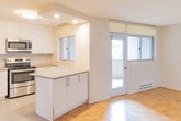 Located at 30 Denton Ave in Toronto's Upper Beaches neighbourhood, this efficiently designed unit offers a well-considered layout across a single floor. Classic parquet flooring runs throughout the main living area, adding warmth and character to the bright, open space. A large window allows natural light to fill the living area, creating an airy and welcoming atmosphere.

The kitchen is thoughtfully appointed with white cabinetry, neutral stone-effect countertops, and stainless steel appliances including a refrigerator and electric range. A window above the counter brings in additional natural light and offers a pleasant outdoor view of surrounding greenery, making the kitchen a functional and inviting workspace.

A hallway connects the key areas of the unit, lined with doors leading to the closet and bathroom. The bathroom is finished to a modern standard, featuring a glass-enclosed walk-in shower with white tile surround, mosaic tile flooring, chrome fixtures, and grab bars for added accessibility. A vanity with an integrated sink completes the space.

The closet provides practical storage, while the overall layout maximizes the use of the available floor area. The unit's clean, neutral palette and consistent finishes throughout make it a versatile and comfortable living space.
