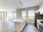 Located at 220 Vine in Columbus, Ohio, this thoughtfully designed 2-bedroom, 2-bathroom residence offers a comfortable and contemporary living experience across a single floor. The open-concept kitchen and living area serves as the heart of the home, showcasing light wood-look flooring, neutral warm-toned walls, and abundant natural light from multiple windows. The kitchen is equipped with white cabinetry, a subway tile backsplash, stainless steel appliances including a range, microwave, and refrigerator, and a central island with a built-in sink and white quartz countertop — ideal for both cooking and casual dining. Track lighting overhead adds a modern touch. A dedicated closet discreetly houses a stacked washer and dryer, adding everyday convenience. The spacious primary bedroom features large windows and hardwood-style flooring, while both bedrooms offer plush carpeting and ample natural light. Two well-appointed closets provide generous storage, with wire shelving systems for organization. The bathroom includes a full tub-shower combination, a white vanity with dark hardware, and wood-look flooring. The overall aesthetic is clean, modern, and move-in ready, making this residence a polished urban home in the heart of Columbus.