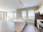 Located at 220 Vine in Columbus, Ohio, this thoughtfully designed 2-bedroom, 2-bathroom residence offers a comfortable and contemporary living experience across a single floor. The open-concept kitchen and living area serves as the heart of the home, showcasing light wood-look flooring, neutral warm-toned walls, and abundant natural light from multiple windows. The kitchen is equipped with white cabinetry, a subway tile backsplash, stainless steel appliances including a range, microwave, and refrigerator, and a central island with a built-in sink and white quartz countertop — ideal for both cooking and casual dining. Track lighting overhead adds a modern touch. A dedicated closet discreetly houses a stacked washer and dryer, adding everyday convenience. The spacious primary bedroom features large windows and hardwood-style flooring, while both bedrooms offer plush carpeting and ample natural light. Two well-appointed closets provide generous storage, with wire shelving systems for organization. The bathroom includes a full tub-shower combination, a white vanity with dark hardware, and wood-look flooring. The overall aesthetic is clean, modern, and move-in ready, making this residence a polished urban home in the heart of Columbus.