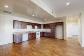 Located at 14105 Chadron Ave in Hawthorne, CA, this single-floor residence offers four bedrooms and two bathrooms thoughtfully arranged across a well-proportioned layout. The open-concept kitchen and living area serves as the heart of the home, showcasing rich dark-wood cabinetry with granite-look countertops, white appliances including a range and dishwasher, and abundant upper and lower cabinet storage. Warm hardwood-style flooring flows consistently throughout the entire home, lending a cohesive and inviting aesthetic. Recessed lighting illuminates the main living and kitchen areas, while a tray ceiling detail adds architectural interest above the kitchen. A sliding glass door brings in natural light and provides outdoor access from the living area. The generously sized primary bedroom features dual closets and its own private bathroom, complete with a tiled shower-tub combination, granite-topped vanity, and tile flooring. The second full bathroom mirrors this design with a shower-tub combo and matching finishes. Additional bedrooms are bright and well-sized, with windows offering views of the surrounding neighborhood. A dedicated closet and accessible electrical panel round out the practical features of this clean, move-in-ready Hawthorne residence.