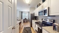 This single-floor residence offers a thoughtfully designed open-concept layout that seamlessly connects the living, dining, and kitchen areas. The living room is bright and welcoming, featuring wood-look flooring, a ceiling fan, and large windows dressed with patterned drapes that allow ample natural light to fill the space. The adjacent dining area provides a dedicated space for meals, highlighted by a pendant light fixture and a window with blinds.

The galley-style kitchen is well-equipped with white cabinetry, granite countertops, a tile backsplash, and a full suite of stainless steel appliances including a refrigerator, electric range, built-in microwave, and dishwasher. Wood-look flooring runs throughout the kitchen, adding warmth and continuity.

The bedrooms are comfortably sized and carpeted, each featuring walk-in closets for generous storage. One bedroom includes a distinctive accent wall in a cool blue tone. The primary bathroom is finished with granite countertops, wood-look flooring, a soaking tub, and direct access to a walk-in closet.

Completing the home is a dedicated laundry room with a full-size washer and dryer, and checkered tile flooring. Throughout the residence, neutral wall tones and consistent finishes create a cohesive and modern living environment.