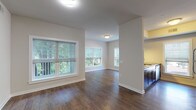 This single-floor residence offers a thoughtfully designed layout with a cohesive blend of modern finishes and functional spaces throughout. The open living and dining area is anchored by rich, dark hardwood flooring that extends through the main common areas, complemented by neutral-toned walls and an abundance of natural light streaming through multiple large windows fitted with horizontal blinds. Views of mature trees provide a pleasant natural backdrop.

The kitchen is positioned adjacent to the living area and features dark espresso cabinetry with sleek bar-pull hardware, dark granite-style countertops, stainless steel appliances including a dishwasher and electric range, and a window overlooking an outdoor common area. A tiled backsplash adds a subtle decorative touch.

The bedrooms are carpeted in a neutral tone, offering a comfortable contrast to the hardwood common areas. Each room includes windows that bring in natural light and outdoor views. An exterior door in the living space provides direct outdoor access.

The bathrooms are finished with large-format light tile flooring, white fixtures, and dark espresso vanities with white countertops. Each bathroom includes a full tub/shower combination and clean, minimalist detailing throughout, contributing to the overall modern and well-maintained character of the space.