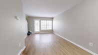 Located at 1100 Deer Path in Lakewood, NJ, this two-story home offers a well-organized layout evenly divided between two floors. The main level features an open-concept living room and kitchen area bathed in natural light through large windows. The living room showcases light wood-style flooring and neutral gray walls, creating a clean, bright atmosphere. The kitchen is equipped with warm-toned wood cabinetry, white appliances including a gas range and refrigerator, and a pass-through counter that connects to the dining area. A staircase with carpeted treads leads to the upper level, where both bedrooms are located. The generously sized primary bedroom offers a sliding-door closet and easy access to the hallway. The second bedroom is bright and airy, highlighted by a large window allowing ample natural light. A walk-in closet with wire shelving provides substantial storage on this floor. Both bathrooms are finished with white vanities, mirror fixtures, and the same consistent light wood-style flooring found throughout the home. The neutral color palette, consistent flooring, and clean finishes lend the space a cohesive, move-in-ready appeal throughout.