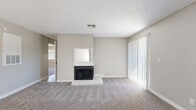 Located at 6551 Annie Oakley Dr in Henderson, NV, this single-floor, 2-bedroom, 2-bathroom home offers a well-organized layout across a comfortable footprint. The living room serves as the heart of the home, featuring a classic wood-framed fireplace with a tiled hearth, soft carpet flooring, neutral beige walls, and a sliding glass door that invites natural light and outdoor access. The kitchen is efficiently designed in a galley style, showcasing white cabinetry, white appliances including a range and refrigerator, light wood-look flooring, and a standout skylight that brightens the space naturally. Both bedrooms are carpeted and finished in the same warm neutral tones, each offering vertical-blind windows for light control and privacy. The primary bedroom is generously sized and includes a built-in closet with sliding doors and integrated shelving for organized storage. A second closet provides additional storage elsewhere in the home. Both bathrooms feature clean white tub-shower combinations with tiled surrounds and light wood-look flooring. A connecting hallway ties the layout together efficiently. Textured ceilings are consistent throughout, and the overall aesthetic is clean, neutral, and move-in ready.