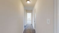 Located in Towson, MD, this single-floor residence features three bedrooms, one bathroom, a kitchen, and two connecting hallways within a compact, efficiently organized footprint. The neutral, cream-toned walls and plush gray carpet throughout the bedrooms and hallways create a clean, understated aesthetic. The spacious primary bedroom is a standout feature, benefiting from three windows that allow abundant natural light and offer views of the surrounding greenery. The two additional bedrooms are well-proportioned, each with carpeted floors, natural light from individual windows, and access to closet space. A carpeted hallway with a flush ceiling light connects the rooms and leads toward the main living areas. The kitchen is equipped with rich dark wood cabinetry, granite-style countertops, a black electric range, a dishwasher, and a stainless steel sink — all complemented by warm hardwood flooring and a window for natural light. The bathroom features classic white subway tile wainscoting, a tub-shower combination, a wood vanity with a white countertop, a mirrored medicine cabinet, and a window for ventilation. Together, these elements make for a practical and comfortable living space.