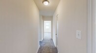 Located in Towson, MD, this single-floor residence features three bedrooms, one bathroom, a kitchen, and two connecting hallways within a compact, efficiently organized footprint. The neutral, cream-toned walls and plush gray carpet throughout the bedrooms and hallways create a clean, understated aesthetic. The spacious primary bedroom is a standout feature, benefiting from three windows that allow abundant natural light and offer views of the surrounding greenery. The two additional bedrooms are well-proportioned, each with carpeted floors, natural light from individual windows, and access to closet space. A carpeted hallway with a flush ceiling light connects the rooms and leads toward the main living areas. The kitchen is equipped with rich dark wood cabinetry, granite-style countertops, a black electric range, a dishwasher, and a stainless steel sink — all complemented by warm hardwood flooring and a window for natural light. The bathroom features classic white subway tile wainscoting, a tub-shower combination, a wood vanity with a white countertop, a mirrored medicine cabinet, and a window for ventilation. Together, these elements make for a practical and comfortable living space.