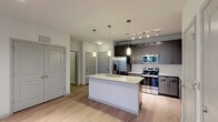 This well-appointed 2-bedroom, 2-bathroom residence offers a thoughtfully designed single-level layout that balances style and functionality. The open-concept kitchen serves as the heart of the home, showcasing dark gray cabinetry, granite countertops, a subway tile backsplash, and a full suite of stainless steel appliances including a French door refrigerator, electric range, and built-in microwave. A central kitchen island with an integrated sink and pendant lighting above adds both workspace and visual appeal. Wood-style plank flooring flows throughout the main living areas, complemented by track lighting that brightens the open space.

Both bedrooms offer plush carpeting, ceiling fans, and windows that allow natural light to filter in. Each room includes closet access, providing ample storage. The two bathrooms are finished with matching dark gray vanities, granite countertops, framed mirrors, and wood-style flooring. One bathroom features a soaking tub with large-format dark tile surround and direct access to a walk-in closet, while the second bath offers a clean, streamlined design. Double doors in the living area open to additional storage. The overall aesthetic is modern and cohesive, with a neutral palette throughout.