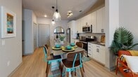 Located at 1601 Central Ave in the heart of St. Petersburg, Florida, this single-floor residence offers a thoughtfully designed layout with modern finishes and a cohesive contemporary aesthetic throughout.

The open-concept kitchen serves as the centerpiece of the living space, outfitted with crisp white cabinetry, stainless steel appliances including a refrigerator, electric range, and built-in microwave, and a quartz-topped island with an undermount sink. Stylish pendant lighting hangs above the island, which also functions as a dining and gathering space with bar-style seating. Light wood-tone flooring runs through the kitchen and living areas, adding warmth to the clean, modern palette.

The bedroom is a serene retreat featuring plush carpeting, a ceiling fan, and a generously sized window dressed with colorful patterned curtains that allow for ample natural light while maintaining privacy. The room offers a calm, restful ambiance well-suited for relaxation.

The bathroom is finished with white cabinetry, a quartz countertop vanity, light wood-tone flooring, and a glass-enclosed walk-in shower with white tile surround. The clean lines and neutral tones create a spa-like atmosphere.

The dollhouse view reveals an efficient, well-connected floor plan that maximizes functionality, with a laundry area also present within the unit. This residence combines practical design with contemporary style in a prime St. Petersburg location.
