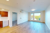 Located along San Tomas Expressway in Santa Clara, CA, this single-floor unit offers a clean, contemporary design throughout. Light-toned hardwood flooring runs continuously across the living, dining, and bedroom areas, creating a cohesive and airy feel. The open living area is bright and generously proportioned, with large windows and a glass door that invite abundant natural light and frame views of the surrounding greenery.

The kitchen is well-appointed with rich warm-toned wood cabinetry, white appliances including a refrigerator, electric range, and dishwasher, complemented by recessed ceiling lighting and a double sink. A wall-mounted mini-split climate control system ensures year-round comfort in both the living area and bedrooms.

The bedrooms are calm and well-lit, each featuring hardwood floors, windows with outdoor views, and dedicated closet space — including a spacious walk-in closet with wire shelving. The bathroom is outfitted with a full tub and shower combination, a curved shower rod, grab bars, built-in shelving, and a wood-accented vanity with a white countertop. The unit's clean white walls and minimalist design maintain a bright, welcoming ambiance throughout.