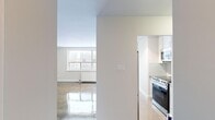 Located on the fourth floor at 2222 Weston Rd in Toronto's Weston neighbourhood, this one-bedroom, one-bathroom unit offers a well-designed layout across a single floor. The living area is bright and airy, benefiting from a large window that frames views of the surrounding cityscape, while warm parquet flooring adds character and texture to the space. The kitchen is efficiently laid out with white cabinetry, grey countertops, light tile flooring, and a full suite of stainless steel appliances including a gas range, built-in microwave, and refrigerator. Recessed track lighting illuminates the kitchen, giving it a clean, modern feel. The spacious primary bedroom features the same rich parquet flooring, neutral walls, and a classic panelled white door, offering a calm and comfortable retreat. The bathroom is tastefully finished with white subway tile extending from floor to ceiling around the soaking tub and shower, complemented by a dark wood vanity with a white countertop, a large mirror, and contemporary pendant lighting. A welcoming hallway connects all rooms, completing this cohesive and functional unit ideal for urban living in Toronto.