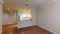 This single-floor residence offers a functional and comfortable layout with a clean, classic aesthetic carried throughout each room. The open living area welcomes you with warm hardwood-style flooring, crown molding, and a large window that invites natural light into the space. A paneled front door with tile entry transitions seamlessly into the main living area, creating an inviting first impression.

The kitchen is thoughtfully designed with a peninsula breakfast bar featuring dark granite-style countertops, white cabinetry, and track lighting overhead. A full suite of white appliances — including a refrigerator, electric range, microwave, and dishwasher — lines the galley-style kitchen, complemented by a stainless steel sink and ample cabinet storage on both sides.

The bedroom is finished with plush carpeting and neutral walls, and features a spacious walk-in closet equipped with built-in shelving and hanging rods, providing generous storage capacity.

The bathroom includes a single-sink vanity with white cabinetry, a tiled tub-shower combination, and hardwood-style flooring that continues the cohesive design language of the home. Crown molding and consistent warm beige tones throughout the space contribute to a calm and well-maintained atmosphere.