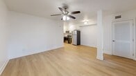 Located at 227 S Armenia Ave in Tampa's desirable 33609 zip code, this one-bedroom, one-bathroom unit presents a thoughtfully designed layout that maximizes its intimate footprint. Light wood-tone flooring runs throughout the entire space, creating a cohesive and bright aesthetic that enhances the sense of openness.

The combined living room and kitchen area forms the heart of the unit. The living space features white walls, a ceiling fan with light fixture, a decorative column accent, and windows with blinds that allow natural light to filter in. The kitchen is well-appointed with stainless steel appliances including a refrigerator, electric range, over-the-range microwave, and a built-in wine cooler. White upper cabinetry contrasts with dark wood-tone lower cabinets, complemented by granite-style countertops and a white subway tile backsplash.

The generously sized primary bedroom includes a ceiling fan, a large sliding-door closet, and a window providing natural light. The bathroom features a tub-shower combination with white tile surround accented by a mosaic tile border, a dark wood vanity with white countertop, and wood-look tile flooring.