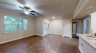 This single-story, one-bedroom, one-bathroom unit offers a thoughtfully designed layout across a compact yet functional footprint. The open-concept living and kitchen area is anchored by rich, dark hardwood-style flooring and warmed by neutral beige walls throughout. Crown molding adds a refined architectural touch, while a ceiling fan with a light fixture provides both comfort and ambient lighting. Natural light flows in through multiple windows and a set of French doors, offering pleasant outdoor views and a bright, airy atmosphere.

The kitchen features warm wood cabinetry, granite-style countertops, stainless steel appliances including a refrigerator, microwave, and range, and a peninsula with a built-in sink that opens toward the living area — making it well-suited for both cooking and entertaining.

The bedroom is a comfortable, carpeted retreat with a ceiling fan, a window with outdoor views, and access to a spacious walk-in closet outfitted with wire shelving and additional storage space. The bathroom includes a full tub-shower combo with white tile surround, rich wood cabinetry, and granite-style countertops. A dedicated laundry area with an in-unit washer and overhead shelving completes this practical and well-equipped space.