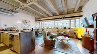 Located in the heart of Oklahoma City's vibrant downtown, this urban loft on Dean A McGee Avenue showcases an impressive industrial-chic aesthetic across a single, thoughtfully designed floor. Soaring ceilings with exposed concrete beams, warm wooden trusses, and visible ductwork give the space a dramatic, warehouse-inspired character throughout.

The expansive open-concept main area seamlessly integrates the living room, dining room, and kitchen. Large windows along one wall flood the space with natural light while offering views of the surrounding Oklahoma City skyline. The kitchen features granite countertops, stainless steel appliances, and a breakfast bar with sleek pendant lighting overhead.

The generous bedroom area benefits from the same soaring ceilings and is complemented by a dedicated office space and ample closet storage. A dedicated workspace with built-in cabinetry provides a functional home office setup.

The bathroom is well-appointed with slate tile flooring, a granite vanity with wood cabinetry, and a tiled tub-shower combination. Light wood flooring flows consistently throughout the living areas, tying the rooms together cohesively.

With its open layout, striking architectural details, abundant natural light, and urban downtown location, this loft offers a distinctive and dynamic living environment.