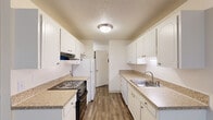 Located on SW Laurelwood Drive in Portland, Oregon, this single-floor, three-bedroom, one-bathroom home offers a practical and comfortable layout. The galley-style kitchen is a standout feature, lined with white cabinetry, granite-style countertops, and wood-look flooring. It is equipped with a range, refrigerator, and a stainless steel sink, with a range hood overhead and a textured ceiling throughout. The kitchen flows into a dining area with a ceiling fan and a window overlooking greenery, filling the space with natural light. The living room is carpeted and generously sized, featuring a sliding glass door that opens to an outdoor patio area with views of a manicured lawn. Baseboard heating runs along the walls, ensuring year-round comfort. Each of the three bedrooms is carpeted, with neutral walls and textured ceilings. The bedrooms offer closet storage, and several rooms receive natural light through windows. The full bathroom features wood-look tile flooring, a granite-style vanity countertop, and a tub-shower combo with stone-patterned tile surround. A hallway connects the main living areas, keeping the floor plan efficient and cohesive throughout.