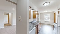 Located at 650 York Creek Dr NW in Comstock Park, Michigan, this single-floor, 2-bedroom, 2-bathroom unit offers a practical and well-organized layout. The galley-style kitchen is a standout feature, lined on both sides with warm honey-toned wood cabinetry, granite-patterned countertops, a double stainless steel sink, and white appliances including a range and built-in microwave. Light wood-look flooring runs through the kitchen and dining area, which is brightened by a window overlooking the exterior. The living room provides a comfortable gathering space with plush carpeting and a dedicated exterior door, offering convenient access to the outdoors. Both bedrooms are carpeted and feature neutral wall tones, natural light from windows, and ample space. The spacious primary bedroom includes its own closet, while the second bedroom also benefits from dedicated closet storage — two closets total across the unit. Each bathroom is equipped with a vanity featuring granite-style countertops, warm wood cabinetry, and a shower-tub combination. A hallway connects the main areas, and the consistent use of warm wood door and trim accents throughout gives the unit a cohesive, welcoming character.