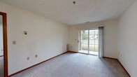 Located at 17465 W River Birch Dr in Brookfield, Wisconsin, this single-floor, 2-bedroom, 2-bathroom residence offers a functional and straightforward layout designed for comfortable everyday living. The interior features neutral-toned walls throughout, accented by warm wood trim and baseboards that lend a cohesive look to each room.

The living area is carpeted and bathed in natural light courtesy of a sliding glass door that opens to an outdoor patio, offering views of the surrounding greenery. The primary bedroom is a well-proportioned space with a large window overlooking the outdoors and direct access to a walk-in closet outfitted with wire shelving and built-in storage tiers, providing ample organization. The second bedroom is similarly carpeted with its own window that brings in natural light and neighborhood views.

Both bathrooms are finished with light-toned flooring and include vanities with wood cabinetry, a toilet, and a tub/shower combination with sliding glass enclosures. A connecting hallway ties the bedrooms and bathrooms together, creating a clear and efficient circulation path. The textured ceilings and consistent use of carpet in the main living spaces contribute to a quiet, low-maintenance atmosphere throughout this Brookfield residence.