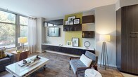Located at 2009 N 14th Street in Arlington, VA, this contemporary single-floor residence showcases a thoughtfully designed open layout with modern finishes throughout. The living area is anchored by expansive floor-to-ceiling windows that flood the space with natural light and offer views of the surrounding urban greenery and skyline. A sleek built-in wall unit with dark wood and high-gloss cabinetry provides stylish storage and display space, complementing the warm hardwood-style flooring that runs throughout.

The kitchen is outfitted with dark wood cabinetry, a mosaic tile backsplash, stainless steel appliances including a range, microwave, dishwasher, and refrigerator, and a clean white countertop island with bar seating — ideal for both meal preparation and casual dining. Track lighting overhead enhances the kitchen's modern aesthetic.

The bedroom is a tranquil retreat, featuring large corner windows that invite abundant natural light and views of the tree-lined streetscape. A dramatic full-wall photographic mural serves as a striking focal point, adding artistic depth to the room. Hardwood-style flooring continues here, contributing to the cohesive design.

The bathroom is finished with large-format tile flooring, dark wood vanity cabinetry, a clean white countertop, and a frameless glass walk-in shower, combining function with refined style.