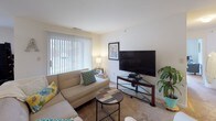 This single-floor residence offers a practical and comfortable layout with clearly defined living spaces finished in neutral tones throughout. The living room serves as the central gathering area, featuring carpet flooring, a large sliding glass door framed by vertical blinds, and an adjacent dining area visible through an open passageway, allowing natural light to flow freely between spaces.

The kitchen is equipped with warm oak cabinetry providing ample storage, white appliances including a refrigerator, electric range, and dishwasher, and tile flooring that continues a cohesive design thread through the home. A pantry closet adds additional storage convenience.

The bedrooms are carpeted and benefit from natural light through large windows dressed with blinds and curtain panels. The primary bedroom is notably spacious, featuring dual windows and room for a seating area or workspace. Additional bedrooms offer comfortable proportions suitable for various uses.

Two full bathrooms serve the residence, each featuring oak vanity cabinetry with integrated sinks, tile flooring, a toilet, and a shower-tub combination enclosed by a curtain. The overall design is clean, bright, and functional, creating a welcoming and livable environment.