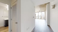 Located on the 14th floor at 813 S Hope St in downtown Los Angeles, this one-bedroom, one-bathroom unit offers a well-designed layout with modern finishes throughout. The living area is a standout, featuring floor-to-ceiling sliding glass windows that flood the space with natural light and frame sweeping views of the Los Angeles skyline. An exposed concrete ceiling adds an industrial-modern character to the room, complemented by a ceiling fan and smooth wood-style flooring in cool gray tones. The kitchen is thoughtfully appointed with dark wood cabinetry, white quartz countertops, a glass tile backsplash, and stainless steel appliances including a range and over-the-range microwave. The bedroom offers a comfortable footprint with warm-toned wood-style flooring, crisp white walls, and an exposed concrete ceiling detail that echoes the living area's aesthetic. A dedicated closet provides organized storage with built-in shelving. The bathroom features a sleek dark wood vanity with white quartz countertop, an undermount sink, and a large mirror. Wood-style flooring continues throughout, tying the space together cohesively. A hallway connects the rooms efficiently, completing this well-appointed urban residence.