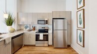 Located at 30 Market St SW in the heart of downtown Concord, NC, this one-bedroom, one-bathroom residence offers a thoughtfully designed layout with contemporary finishes throughout. The open-concept kitchen and living area serves as the centerpiece of the home, featuring warm wood-look flooring that flows seamlessly through the main living spaces. The kitchen is equipped with stainless steel appliances, light wood cabinetry, granite countertops, a peninsula with pendant lighting, and a built-in sink — ideal for both everyday cooking and casual dining. The living room is bright and inviting, bathed in natural light from large windows with views of the surrounding downtown cityscape. Neutral toned walls and clean lines create a calm, modern ambiance throughout. The bedroom offers plush carpeting, a dedicated closet, and a window framing urban views, providing a comfortable and quiet retreat. The bathroom is finished with wood-grain cabinetry, granite countertops, a large mirror, and a full tub-shower combination with subway tile surround and wood-look flooring. A dedicated closet adds practical storage to complement the efficient and functional floor plan of this centrally located residence.