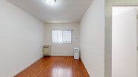 Located at 6212 La Mirada Ave in the vibrant East Hollywood neighborhood of Los Angeles, this single-floor studio unit offers a well-organized layout comprising a living area, kitchenette, and bathroom. The living area features warm-toned hardwood flooring that runs throughout, clean white walls, and a textured ceiling with flush-mounted lighting. A window dressed with vertical blinds allows natural light to filter in, brightening the compact but functional space. Heating and portable air conditioning units are in place to ensure year-round comfort. The kitchenette is thoughtfully designed with modern wood-grain cabinetry, a mosaic tile backsplash, a single-basin sink, a two-burner cooktop, an over-the-range stainless steel microwave, and a compact stainless steel refrigerator — all set atop light tile flooring that transitions seamlessly from the living area. The bathroom continues the clean, minimal aesthetic with light tile flooring, white walls, and a window with vertical blinds providing ventilation and natural light. This unit offers a straightforward, no-frills layout suited for practical, efficient urban living in a well-connected Los Angeles location.