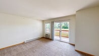 Located at 1420 Commons Dr in Woodstock, Illinois, this one-bedroom, one-bathroom unit offers a well-organized and functional layout across a single floor. The open-concept kitchen and living area form the heart of the unit, with warm hardwood-style flooring in the kitchen transitioning to plush carpeting in the living space. The kitchen is equipped with rich medium-toned wood cabinetry, dark granite-style countertops, a peninsula breakfast bar, and white appliances including a refrigerator, electric range, and dishwasher — providing ample storage and prep space. The living room is generously sized, featuring a wall-unit air conditioner, baseboard heating, and a sliding glass door that opens to a private balcony with outdoor views, allowing natural light to fill the room. A dedicated entry closet adds convenient storage near the front door. The spacious primary bedroom features soft carpeting, baseboard heating, a wall-unit air conditioner, a large window overlooking the outdoors, and a closet with built-in shelving. The bathroom includes a full soaking tub with a clean white surround, integrated shelving, and a curtain rod. The unit's neutral palette and practical design create a comfortable, move-in-ready living environment.